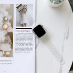transparent TPU watchband for Apple Watch displayed on a table beside a magazine and coffee cup.