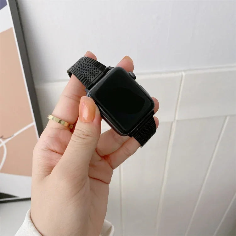 Buckle style steel replacement watchband for Apple Watch, showing a hand holding a black watch with a mesh strap.