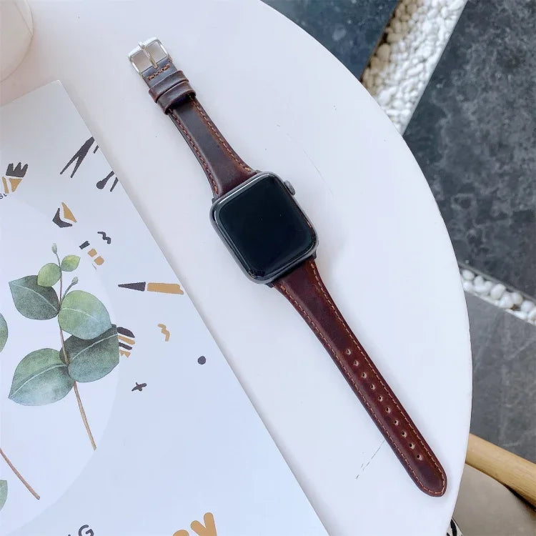 Double-sided genuine leather apple watch band shown on a table beside a notebook with leaves.